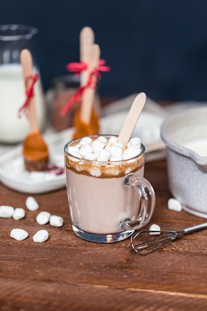 Heißer Kakaolöffel mit gesalzenem Karamell in einer Glasschale mit Marshmallows.