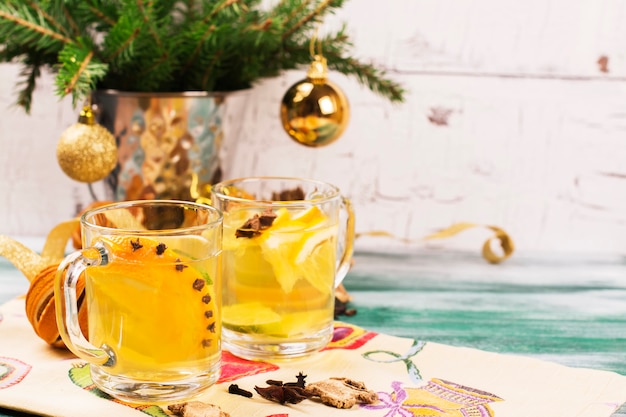 Heißer orange Tee mit Gewürzen in den Glasschalen auf Holztisch.