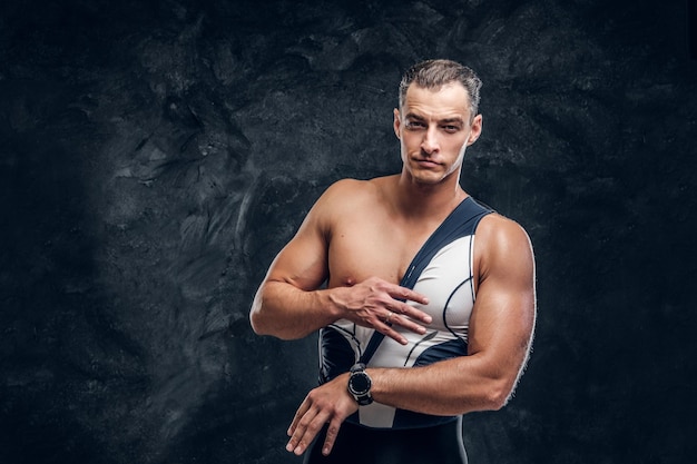 Heißer sexy fitter Mann zieht seinen Neoprenanzug im dunklen Fotostudio aus.