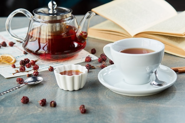 Heißer Tee in Teekanne und Tasse aus Glas, auf dem Tisch