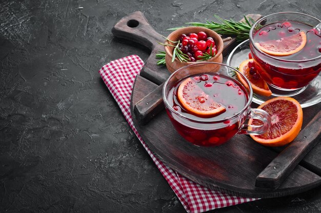 Heißer Tee mit Beeren Cranberry und Orange Auf dem schwarzen Küchenhintergrund Draufsicht Freier Platz für Ihren Text