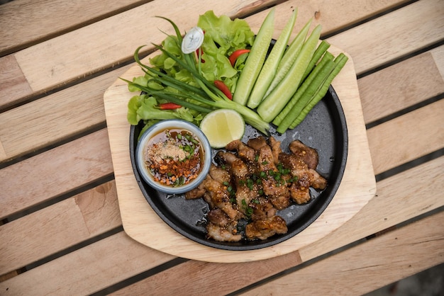 Heißer und würziger gegrillter Schweinefleischsalat (Nam tok moo) auf dem Holztisch