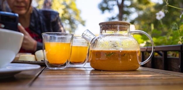 Heißer würziger Sanddorntee in Glasteekanne mit Minzorange und Honig Traditionelles Herbst-Heißgetränk