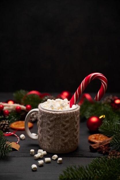 Heißes Kakaogetränk mit Zimtstange und Marshmallows mit Weihnachtsschmuck im Hintergrund