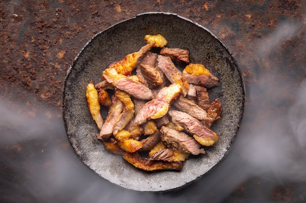 Heißes saftiges geschnittenes Grillrindfiletsteakfleisch in Wabi-Sabi-Artplatte auf rostigem Beschaffenheitshintergrund mit Somke, Draufsicht