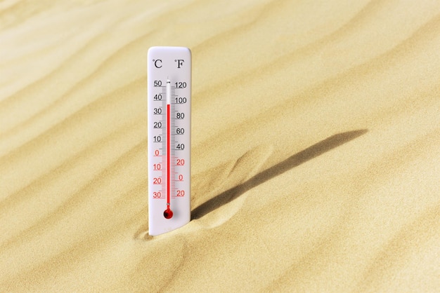 Foto heißes sommertag-thermometer mit celsius-skala im sand. umgebungstemperatur plus 37 grad