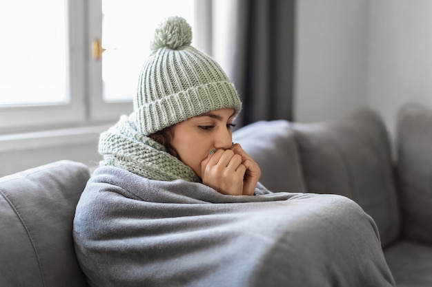 Heizungsprobleme Nahaufnahmeaufnahme einer jungen Frau, die zu Hause einfriert