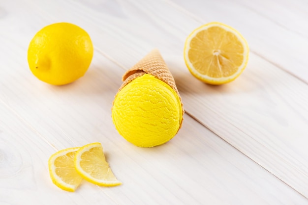 Helado amarillo en un cono con limones en una mesa de madera