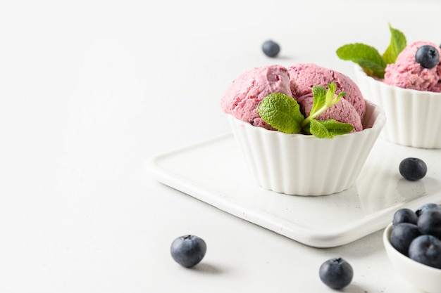 Helado de arándano, sorbete en tazón de fuente en blanco. Espacio para texto.