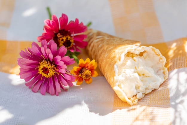 Helado artesanal en cono de galleta y un pequeño ramo de flores en una servilleta de lino en un caluroso día de verano