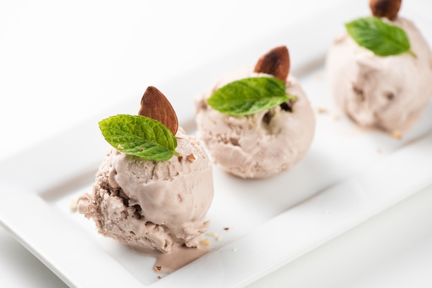 Helado de avellana con nueces sobre un plato blanco y fondo blanco. De cerca