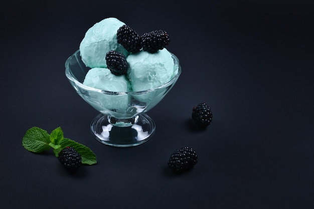 Helado azul en taza con menta sobre negro