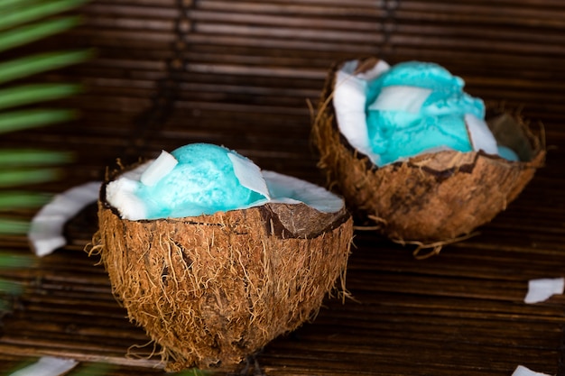 Helado azul en un tazón de coco. Tazón de helado en mitades de nuez sobre fondo de hoja