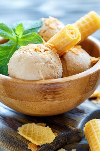 Helado de caramelo y rollos de oblea en tazón de madera