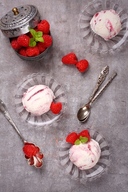 Helado casero de baya decorado con frambuesas frescas sobre fondo gris viejo