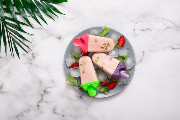 Helado casero en un plato con hielo y trozos de fruta y hojas de palma Vista desde arriba Concepto de verano caluroso