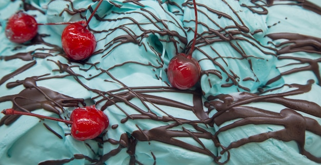 Foto helado casero con sabor a menta azul cubierto con cereza roja y chocolate