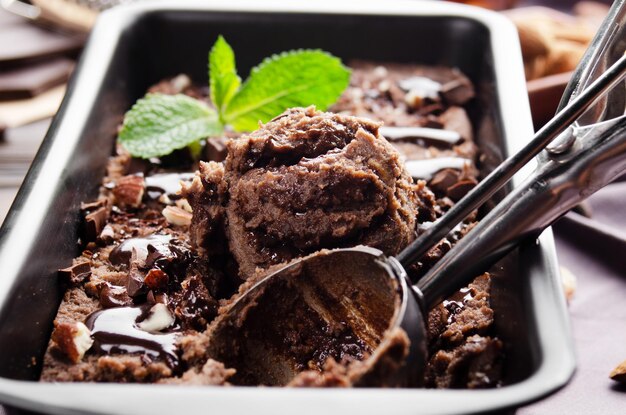 Helado de chocolate en bandeja de metal con hojas de menta y almendras