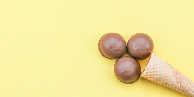 Helado de chocolate con un cono de galleta de tres galletas de caramelo de chocolate sobre un fondo amarillo