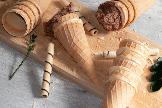 Helado de chocolate, conos de helado y obleas esparcidas sobre la tabla de cortar.