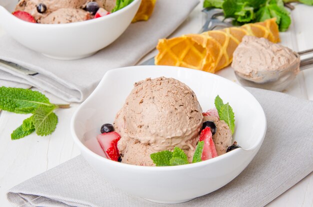 Helado de chocolate cremoso casero en un tazón con fresas y menta