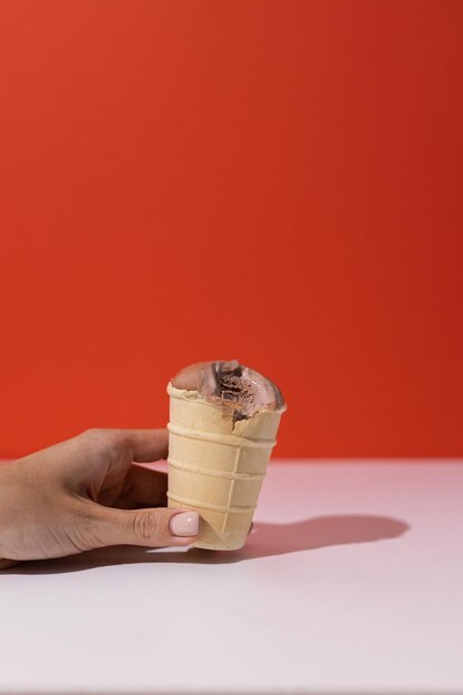 Foto helado de chocolate en una taza de gofres en la mano sobre un fondo rojo goteo libre de lácteos vegetarianos