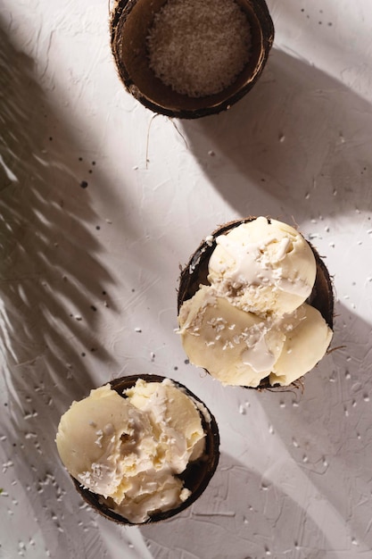 Helado de coco en una cáscara de coco entre las sombras del sol de la mañana