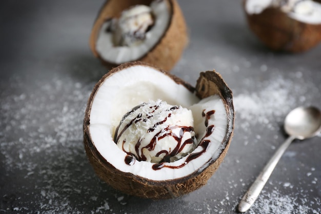 Helado con coco desecado y jarabe de chocolate en la mitad de la nuez sobre fondo grunge