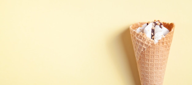 Helado en cono de galleta sobre fondo amarillo.