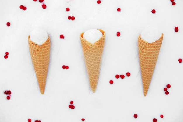 Helado en cono de waffle con bayas rojas de grosella en la nieve