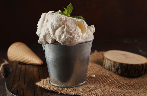 Helado cremoso en balde sobre fondo de madera y arpillera en estilo rústico.