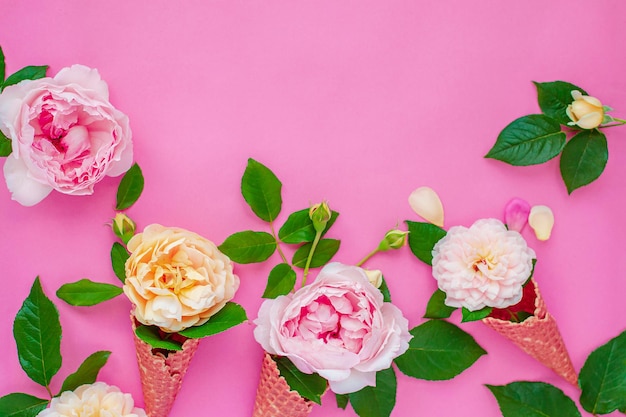 Helado de flores de peonía en un cono de galleta sobre un fondo rosa desde arriba, hermoso arreglo floral, color vintage, endecha plana. Marco floral con lugar vacío para el texto.