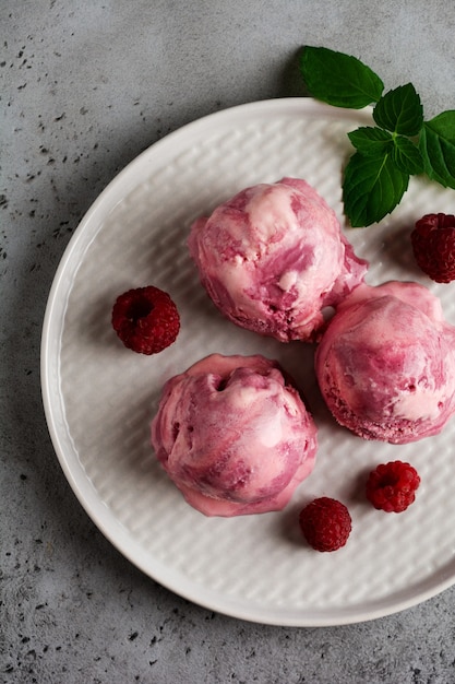 Helado de frambuesa casero con bayas frescas en placa de cerámica gris. Vista superior.