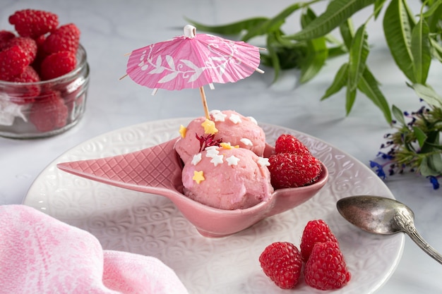 Helado de frambuesa servido en un cuenco rosa sobre una mesa de mármol