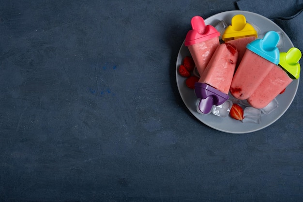 Helado de fresa casero en la mesa de piedra oscura, jugo de fruta congelado, vista superior de estilo vintage