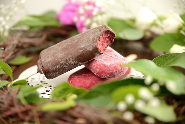 Helado de fruta en un palo, sobre un fondo de hojas verdes