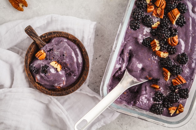 Helado hecho en casa de la baya en un envase de cristal. Helado vegano de moras con nogal y crema de coco.