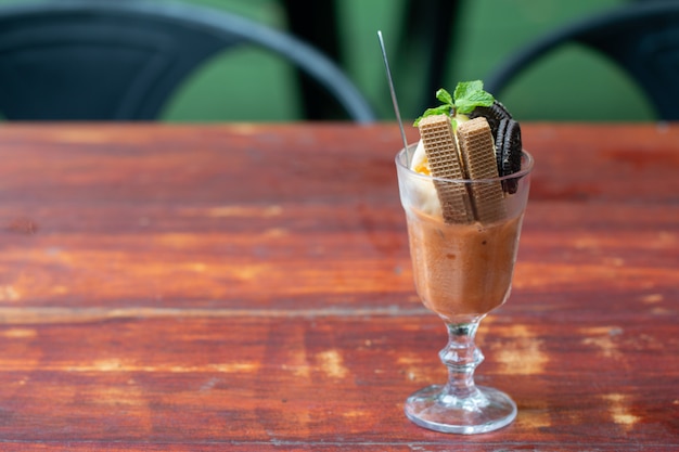 Helado de helado de vainilla con oblea en un vaso servido en un escritorio de madera en la cantina de Asia