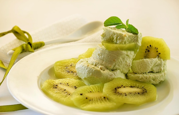 Helado con kiwi en un plato sobre fondo blanco.