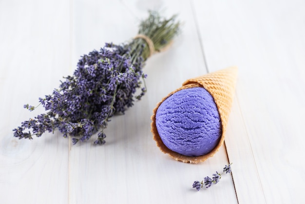 Helado de lavanda en un cono de galleta sobre una mesa de madera