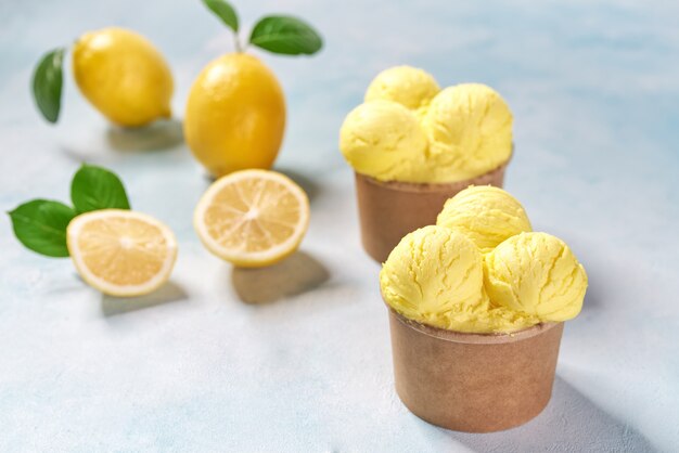 Helado de limón y limón fresco en vaso de papel sobre fondo de colores de menta, vista superior