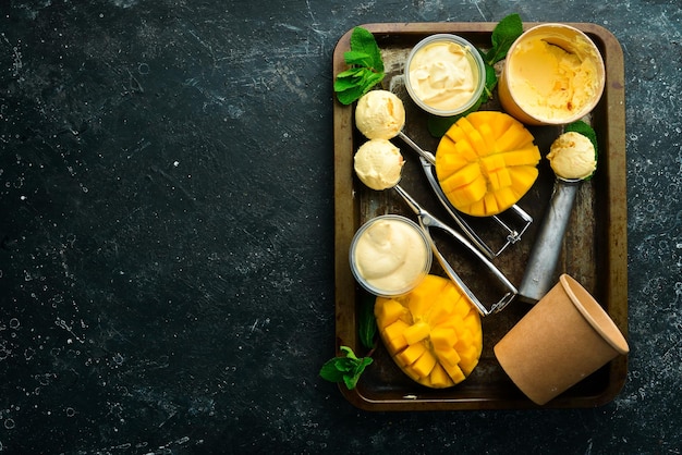 Helado de mango con menta y cuchara de helado de mango fresco En una vista superior de fondo de piedra negra