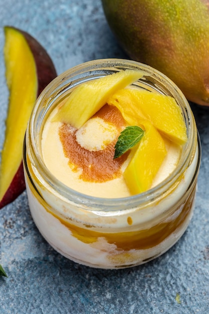 Helado de mango o sorbete en tarro Helado de mango de fruta casero sobre fondo azul helado de postre italiano