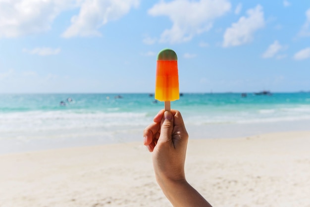 Helado en la mano con fondo de mar - Colorido helado de frutas en la playa en verano clima cálido océano paisaje naturaleza vacaciones al aire libre