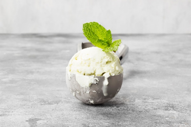 Helado de la menta en cuchara en un fondo gris.