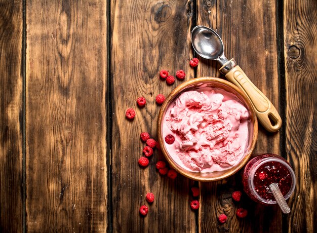 Helado y mermelada de frambuesas silvestres. Sobre una mesa de madera.