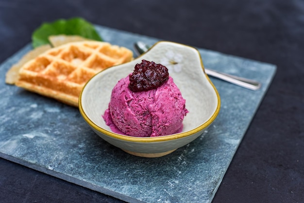 Helado orgánico de hibisco con gofre en plato de piedra con cuchara y tenedor