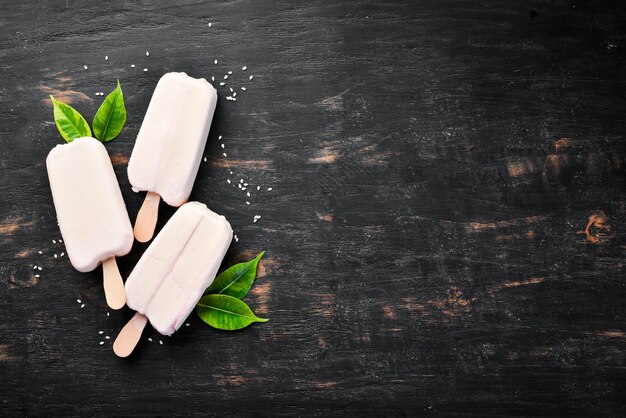 Helado en un palo con chocolate blanco Sobre un fondo negro Vista superior Espacio de copia libre