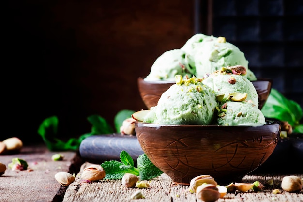 Helado de pistacho con nueces decorado con hojas de menta enfoque selectivo de fondo de madera vintage