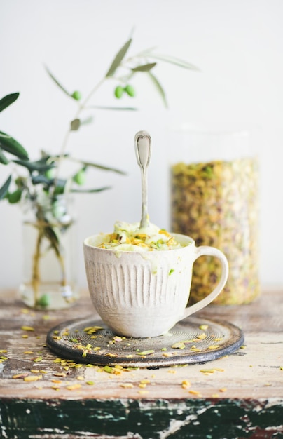 Helado de pistacho con pistachos en taza enfoque selectivo